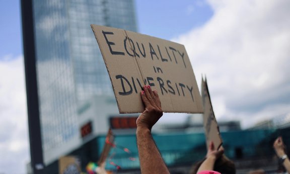 Eine Hand hält ein Schild mit der Beschriftung "Equality in Diversity" hoch