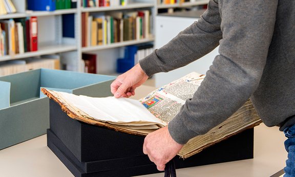 Mann öffnet ein illuminiertes Buch